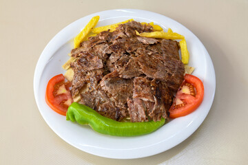 Turkish and Arabic Traditional Ramadan doner kebab with tasty tomato sauce and rice or turkish pilav in white plate on wood table background. ( Pilav ustu doner)