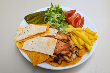 Turkish and Arabic Traditional Ramadan chicken doner kebab with tasty tomato sauce and rice or turkish pilav in white plate on wood table background. (Pilav ustu tavuk doner)
