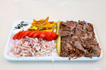 Turkish and Arabic Traditional Ramadan doner kebab with tasty tomato sauce and rice or turkish pilav in white plate on wood table background. ( Pilav ustu doner)