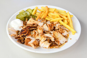 Turkish and Arabic Traditional Ramadan chicken doner kebab with tasty tomato sauce and rice or turkish pilav in white plate on wood table background. (Pilav ustu tavuk doner)