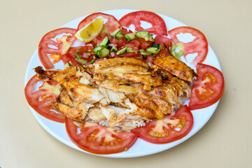 Turkish and Arabic Traditional Ramadan chicken doner kebab with tasty tomato sauce and rice or turkish pilav in white plate on wood table background. (Pilav ustu tavuk doner)