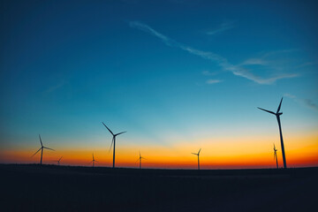 Windmill farm park in silhouettes with colorful sky.