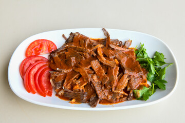 Turkish and Arabic Traditional Ramadan doner kebab with tasty tomato sauce and rice or turkish pilav in white plate on wood table background. ( Pilav ustu doner)