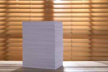Stack of paper sheets on wooden table. Space for text