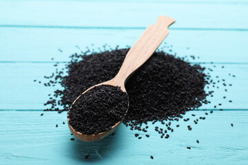Black sesame and spoon on turquoise wooden table, closeup