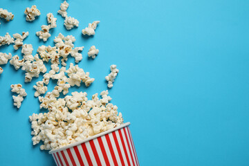 Delicious popcorn on light blue background, top view. Space for text - obrazy, fototapety, plakaty