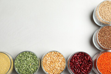 Jars with different cereals on white background, flat lay. Space for text