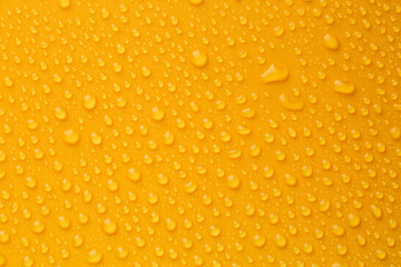 Water drops on orange background, top view