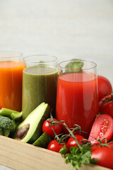Delicious vegetable juices and fresh ingredients on light background, closeup