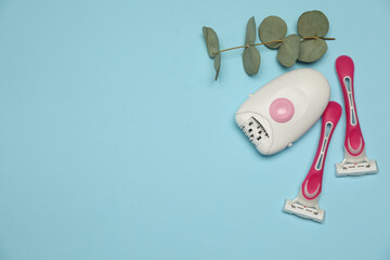 Epilator, razors and eucalyptus on light blue background, flat lay. Space for text