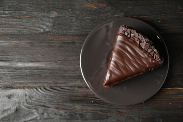 Delicious chocolate cake on black wooden table, top view. Space for text