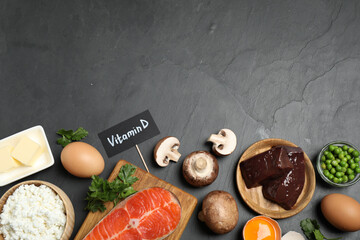 Flat lay composition with products rich in vitamin D on black table. Space for text