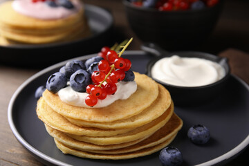 Tasty pancakes with natural yogurt, blueberries and red currants on wooden table