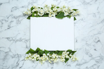 Blank canvas and beautiful jasmine flowers on white marble table, flat lay. Space for design