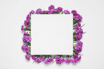 Blank canvas and beautiful violet carnation flowers on white background, top view. Space for design
