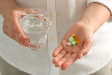 Young woman with glass of water and dietary supplement pills, closeup