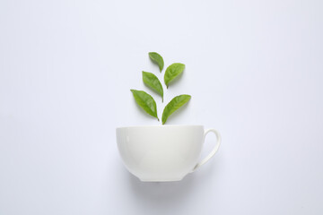 Fresh tea leaves and cup isolated on white