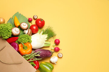 Different fresh vegetables on yellow background, flat lay. Space for text
