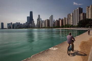 Two people riding bicycles by the Michigan Lake in North Ave Beach with Chicago skyline in the...