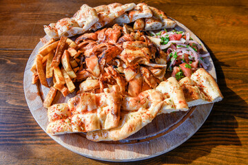 Turkish and Arabic Traditional Ramadan chicken doner kebab with tasty tomato sauce and rice or turkish pilav in white plate on wood table background. (Pilav ustu tavuk doner)