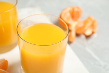 Glass of fresh tangerine juice and fruits on table, closeup