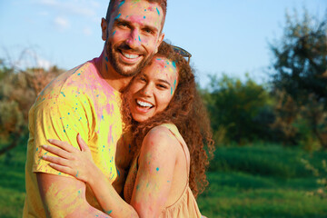 Happy couple covered with colorful powder dyes outdoors. Holi festival celebration