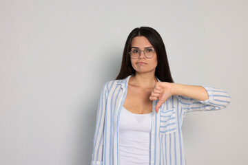 Obraz premium Young woman showing thumb down on white background, space for text