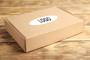 Closed cardboard box with logo on brown wooden table