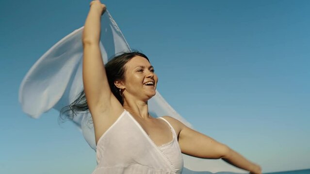 Beautiful young woman girl holding pareo fabric in the wind overlooking the sea