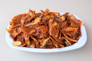 Turkish and Arabic Traditional Ramadan chicken doner kebab with tasty tomato sauce and rice or turkish pilav in white plate on wood table background. (Pilav ustu tavuk doner)