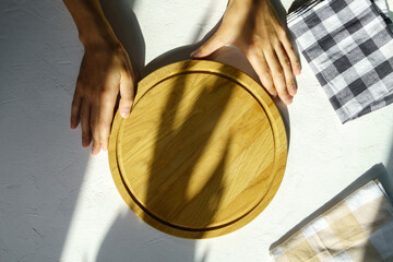 Man hand holding empty round wooden pizza board in hand, white background. Mockup