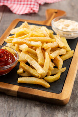 Fried potatoes with ketchup and mayonnaise on wooden table	