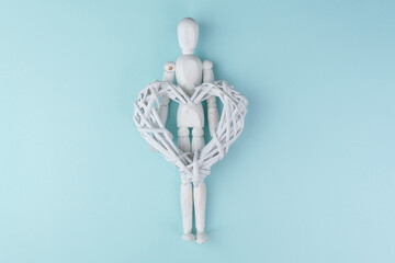 Wooden mannequin with heart. the symbol of happiness. Blue background