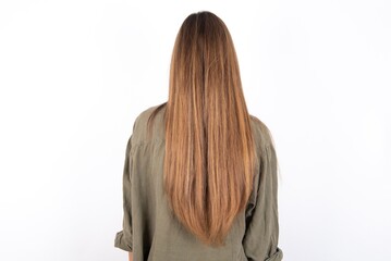 Naklejka premium The back view of a young beautiful woman wearing green overshirt over white background. Studio Shoot.