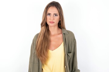 Offended dissatisfied young beautiful woman wearing green overshirt over white background with...