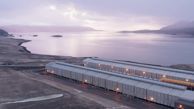 Alcoa Fjarda&aacute;l aluminium smelter on shore of fjord with cloudy sunrise, aerial