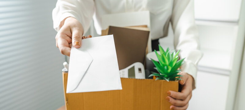 Business woman sending resignation letter and packing Stuff Resign Depress or carrying business cardboard box by desk in office. Change of job or fired from company