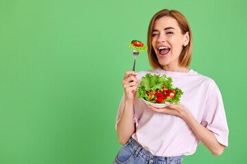 beautiful woman eating fresh vegetable salad on white background