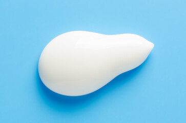 A sample of white moisturizer on a blue background. Cosmetic product for the skin.