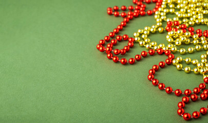 Yellow and red Christmas beads on green background. Copy space