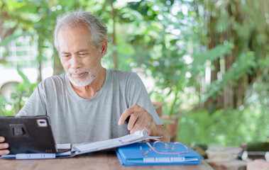 Elderly businessman working in the garden at home and using a tablet
