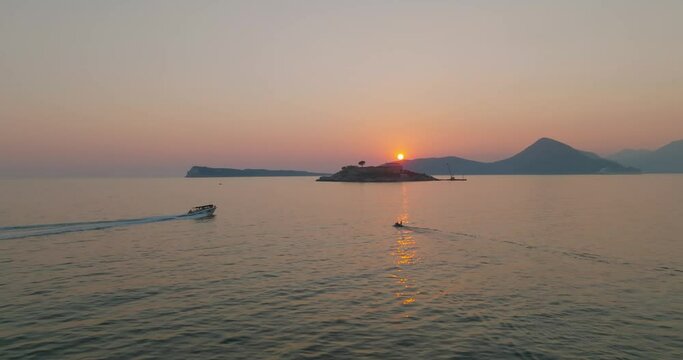 aerial view over the water of mamula island with speeding boats during sunset