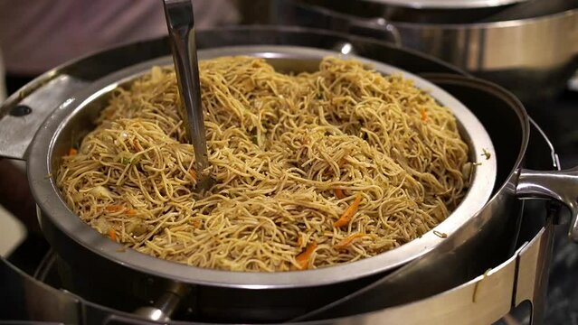 Close up shot of veg noodles made with fresh vegetables like capsicum and spring onion, and served in steel bowl