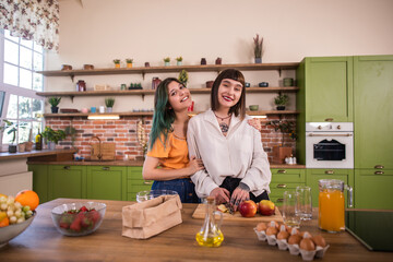 Charismatic two young ladies lesbian couple in the morning get the breakfast together at home in the kitchen they are happy and enjoy the time together concept of LGBT homophobia equality freedom
