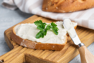 Cream cheese with herbs and seasoning on slice of fresh crunchy rye bread with cheese knife nearby - Powered by Adobe
