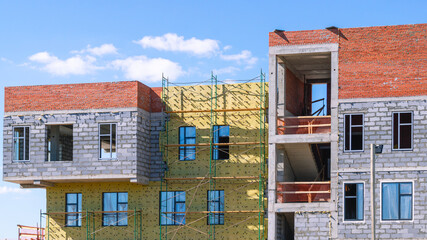 Frame of a building under construction. Construction of buildings in the city. Technologies in the construction of houses. Cladding and insulation of walls on rafters.