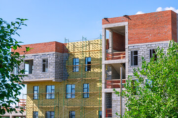 Frame of a building under construction. Construction of buildings in the city. Technologies in the construction of houses. Cladding and insulation of walls on rafters.