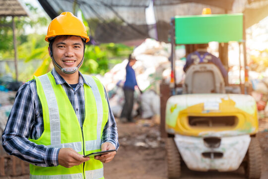 Asian  workers in recycling factory with a forklift on the background, engineers standing in recycling center. Recycle waste, Garbage recycle.