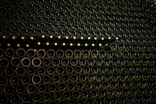 Many glass wine bottles on wine shelves. interior in distillery. Row of Stacked wine bottles in cellar to ferment the wine.