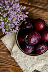 Plums and flowers on a table. Flowers and fruits on a table. Flowers in a vase on a table. Flowers in a vase. 